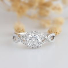 a white gold ring with an oval cut diamond surrounded by smaller round diamonds