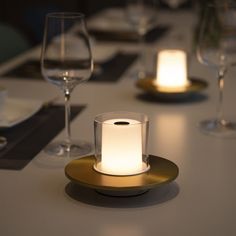 a lit candle sits on top of a plate at a table with wine glasses and silverware