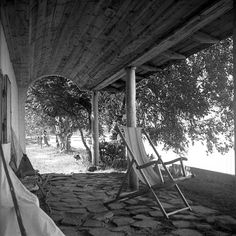 two lawn chairs sitting under a covered porch