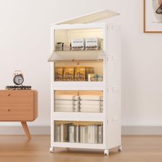 a white book shelf with books on it and a clock sitting on top of it