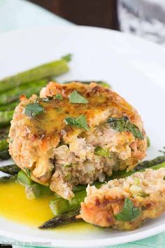 a close up of a plate of food with asparagus and meat patties