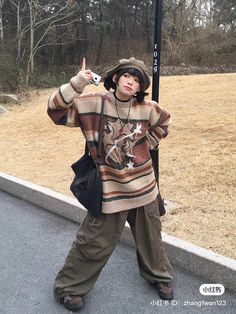 a young boy standing next to a street sign giving the peace sign with his hand