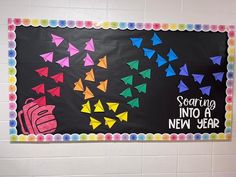 a bulletin board with colorful paper birds and words on it that read soaring into a new year