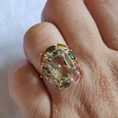 **KINDLY CHECK OUT THE VIDEO OF THE ITEM FOR A CLEARER VIEW**Details of the ring Gem: Tourmaline, green amethyst Gem size: 5x3 mm (9 pec ), 14x10mm Gem shape-oval, cushion Gem weight: 7.15 carats Gold purity: 14KT (58.33% approx.) Gold weight:2.53 gms Total weight of ring:3.96 gms Ring size us 6 Diamond cut Natural Tourmaline with authentic green amethyst Gemstones set in Solid 14KT Yellow Gold. The Gold purity is guaranteed and it comes with authentic 14 kt gold hallmark. Since these Rings are Fine Jewelry Multi-stone Tourmaline Gemstones, Multi-stone Tourmaline Fine Jewelry, Multicolor Tourmaline Rings With Gemstone Accents, Multi-stone Tourmaline Gemstones, Luxury Multi-stone Sapphire Ring With Tourmaline, Handmade Jewelry Box, Green Amethyst Ring, Gold Gemstone Ring, Amethyst Gem