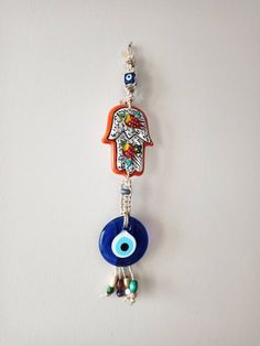 an evil eye charm hangs from a chain on a white wall with beaded beads