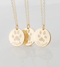 three personalized necklaces with two dogs paw prints on the front and one dog's paw print on the back