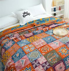 a bed with an orange and blue quilt on it