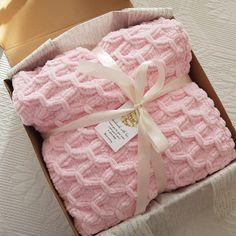 two pink knitted blankets in a cardboard box with a white ribbon on the top