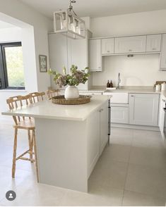 a large kitchen with white cabinets and counter tops, along with a center island in the middle