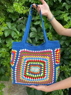 a person holding a crocheted bag in their hand