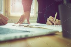 two people sitting at a table with pencils and paper in front of their laptop