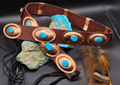 Handmade Concho Belt: Kingman turquoise jewelry gift, unique Handmade Gift for Her, brown leather regalia belt. heirloom jewelry gift. Stamped Copper conchos, With blue Kingman Turquoise. Handmade brown leather belt with 1.75" 12 large hand stamped Copper conchos. Each concho was handmade and stamped and are set with a Kingman turquoise cabochon. Belt ends with black leather ties. Length: 37" tied tight - up to 47". 12 copper conchos: 2.50" x 1.75". Turquoise cabochons:  from 13x16mm - 17x20mm.  Weight: 321 grams. This beautiful Native American belt was hand cut out from a deep mahogany hide.  The 12 Copper conchos were cut, domed and set by Sondra and Marvin with Kingman turquoise Cabochons. The belt ends with black leather strip ties for a beautiful contrast. Boone Silver has the equipme Southwestern Style Brown Jewelry For Festivals, Brown Jewelry With Patina For Festival, Traditional Leather Jewelry For Gifts, Traditional Leather Jewelry As Gift, Unique Brown Jewelry For Ceremonial Occasions, Traditional Leather Jewelry For Festival, Brown Patina Jewelry For Festival, Traditional Handmade Leather Jewelry, Traditional Brown Leather Jewelry