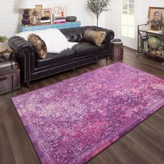 a living room filled with furniture and a purple rug on top of a hard wood floor