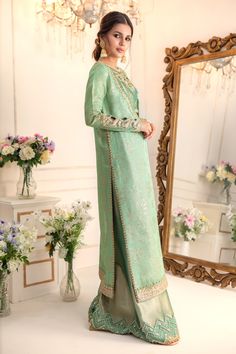 Add a touch of drama & elegance to your wardrobe this wedding season with our stylish ensemble, flowing silhouette paired with zardozi embroidered Blouse & dhaka pants for elongated and sleek look. Stunning embroidered dupatta with pearl & zardozi motifs finishes the look. Shirt & Dupatta Fabric: Pure Embroidered Maysuri NetDhaka Pant & Choli Fabric: Pure soft TissueColor: Caribbean Green This outfit is only available in Custom size, once order is placed design team will contact you for measurem Elegant Jamawar Salwar Kameez For Wedding, Semi-stitched Silk Sets With Dabka Detailing, Elegant Sherwani With Sheer Dupatta For Eid, Elegant Jamawar Sharara For Wedding, Elegant Sets With Dabka Detail For Reception, Raw Silk Dupatta With Dabka For Reception, Reception Dupatta With Dabka On Jamawar, Elegant Sets With Dabka For Reception, Elegant Dabka Sets For Reception