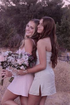 two young women standing next to each other holding flowers