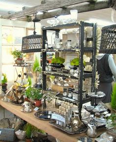 an assortment of pots and pans on display in a room with wooden beams, plants and other items