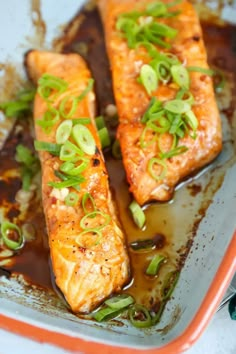 two salmon fillets with brown sauce and green onions