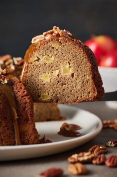 a piece of cake on a plate being lifted by a fork with nuts around it