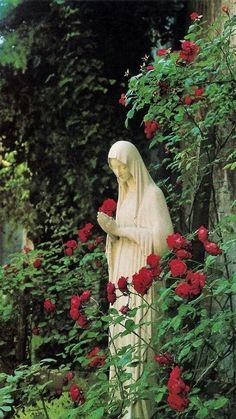 a statue is surrounded by flowers and greenery