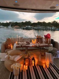 candles are lit on the deck of a boat at night, with tables and chairs set up in front of it