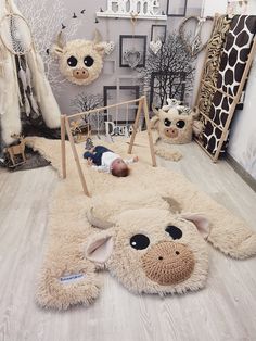 a baby laying on top of a white rug in a room with animal heads hanging from the ceiling