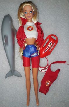 a barbie doll is laying on the floor next to a dolphin and life preserver