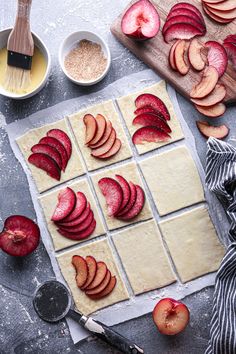 sliced up fruit on top of dough next to bowls and utensils