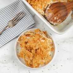 a casserole dish filled with macaroni and cheese next to a wooden spoon