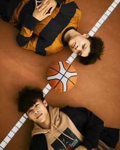 two young men laying on the ground next to each other with basketballs around them