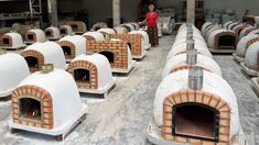 a woman is standing in front of some ovens that are made out of bricks