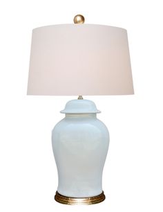 a white table lamp with a gold base and a light blue shade on the top