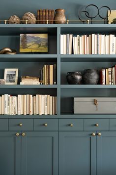 a bookshelf filled with lots of books on top of blue cabinets