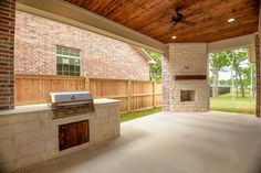 an outdoor kitchen and grill area with brick walls, wood ceilinging, and large sliding glass doors