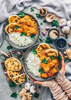 two plates filled with chicken and rice on top of a table next to other dishes