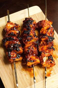 several skewers of meat sitting on top of a cutting board