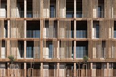 an apartment building with multiple balconies on the front and second story is made out of wooden slats