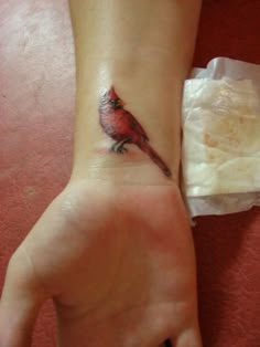 a small red bird tattoo on the wrist