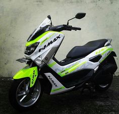 a green and white scooter parked next to a wall