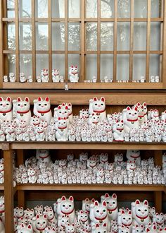 there are many white cat figurines on the shelves in this store that is decorated with red and white polka dots