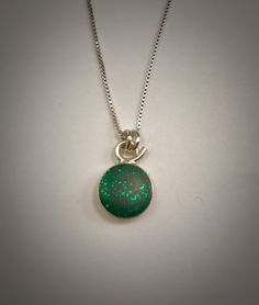 This sterling silver necklace has a tiny emerald green glitter resin pendant. The pendant itself is approximately 3/4 of an inch long by 1/2 of an inch wide. It is on a 16 inch box chain. Other chain lengths are available upon request. I have 16, 18, &20 inch chains. Just send me a convo. This necklace can be duplicated Green Charm Necklace With Round Pendant And Adjustable Chain, Green Charm Necklace With Adjustable Round Pendant, Green Sterling Silver Round Pendant Necklace, Green Pendant Jewelry With Silver Chain, Green Nickel-free Oval Pendant Necklace, Green Nickel-free Pendant Charm Necklace, Green Sterling Silver Charm Necklace With Round Pendant, Green Sterling Silver Charm Necklace, Green Jewelry With Silver Chain As Gift