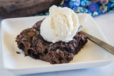 a piece of chocolate cake with ice cream on top is sitting on a white plate