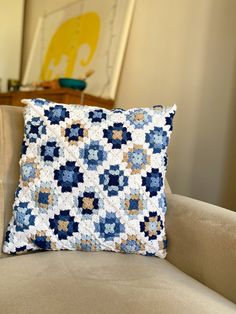 a blue and white pillow sitting on top of a couch