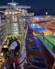 a cruise ship deck at night with lounge chairs and water slides on the other side