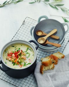 a bowl of soup with bread and spoons next to it on a cooling rack