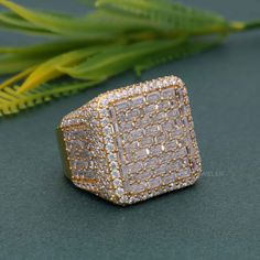 a diamond ring sitting on top of a table next to green plants and leaves in the background