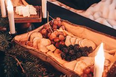 a wooden tray filled with different types of food next to two lit candles on top of a table