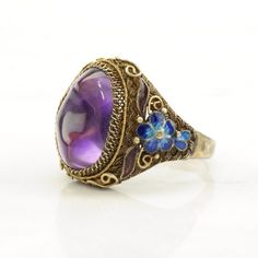 This ring is a size 9 1/2 (USA); It may not be resized Markings: 925 (Tested & guaranteed to be Sterling Silver) This ring weighs 6.8 Grams The Stone/Design is  Amethyst Enamel, Flower, Gold Tone - Natural  The Stone/Design measures 15.5 x 10.9 mm The Ring face measures 22.2 x 19.5 mm The condition of this ring is Estate, Very good, light enamel wear and one chipped enamel area, moderate to heavy patina This vintage item is circa 1950  For more vintage sterling silver rings please visit:  https://www.etsy.com/shop/SilverStarrs925?section_id=13854217 Thank you for viewing my item!  Favorite the store to get updates when items go on sale! Vintage Gemstone Enamel Ring As A Gift, Vintage Enamel Gemstone Ring For Gift, Fine Jewelry Purple Cabochon, Formal Purple Cabochon Ring, Vintage Stamped 925 Amethyst Ring, Heirloom Style Formal Enamel Ring, Vintage Oval Flower Ring Hallmarked, Formal Round Cabochon Enamel Ring, Enamel Gemstone Rings For Wedding