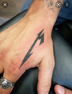 a man's hand with a black lightning symbol tattoo on his left thumb and wrist