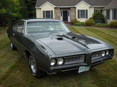 an old muscle car parked in front of a house