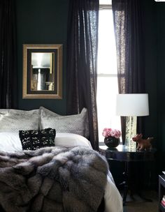 a bedroom with dark green walls and white bedding, two nightstands on either side